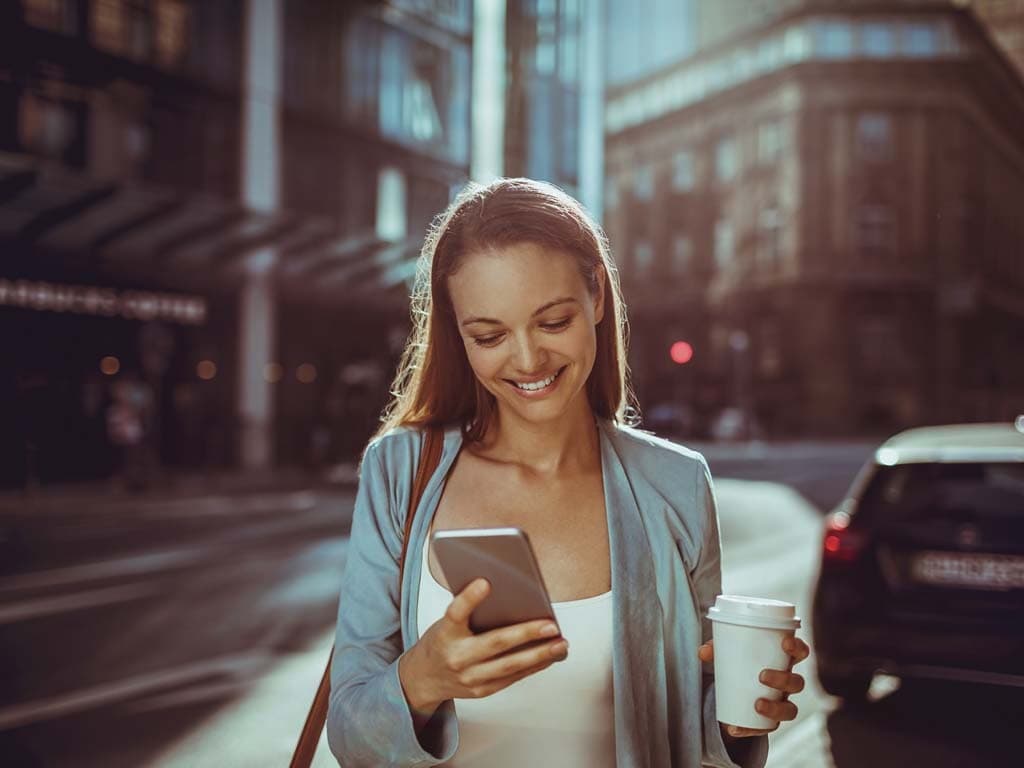 woman smiling with phone and coffee